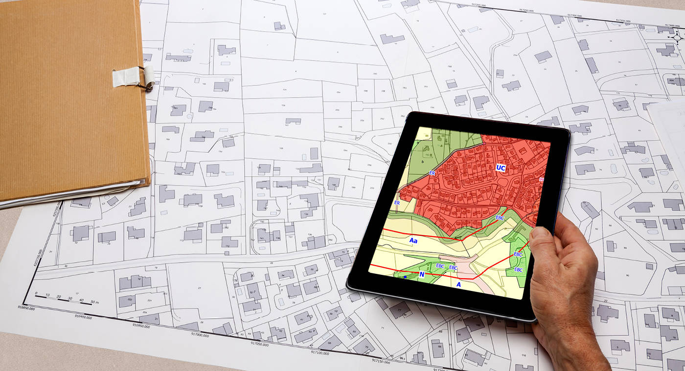 Map represented on a mobile tablet placed on top of a CAD drawing of an urban area
